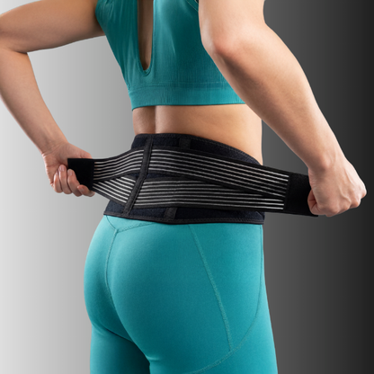 Person wearing a black compression belt over teal athletic wear on a gray background